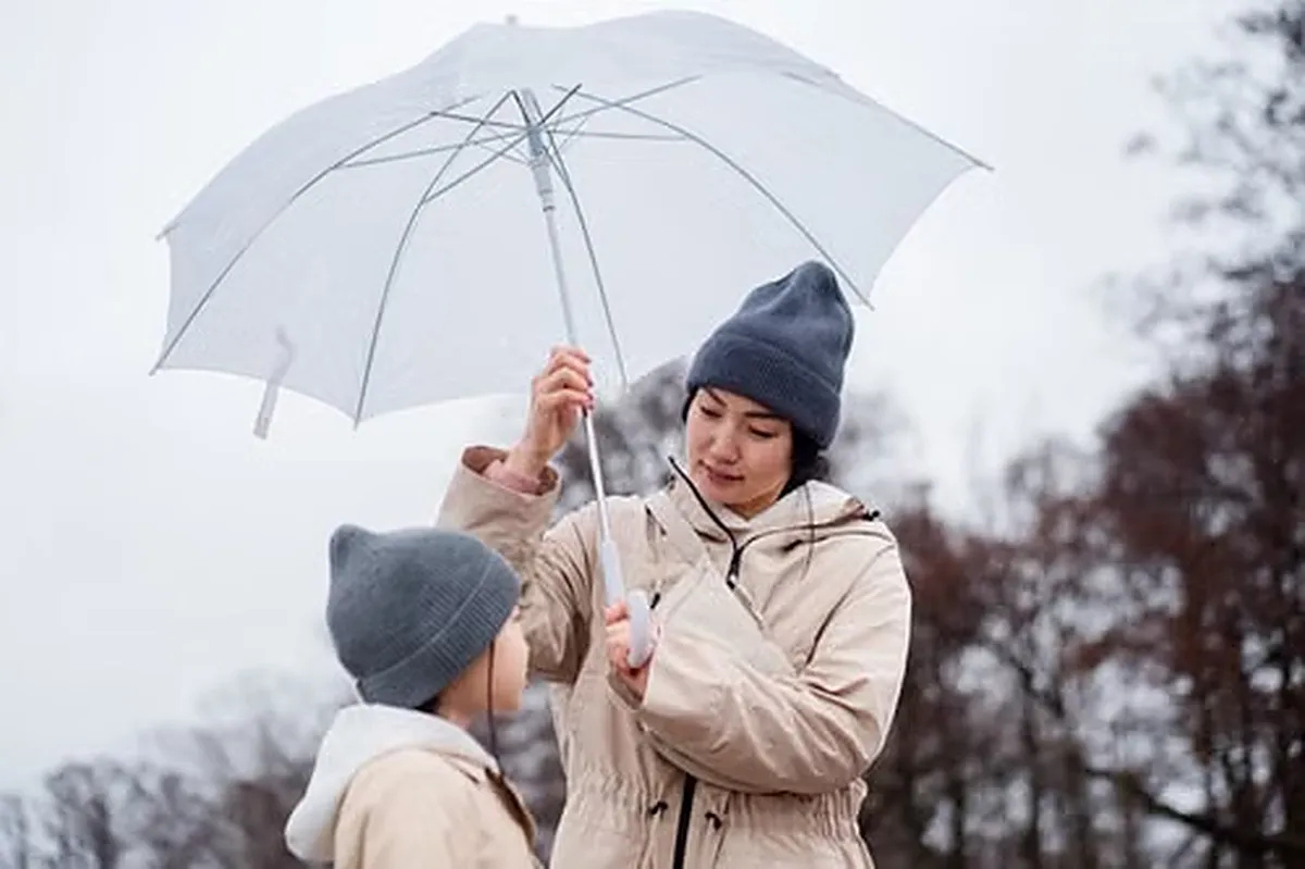 Parent holding a clear umbrella over a child on a rainy day.